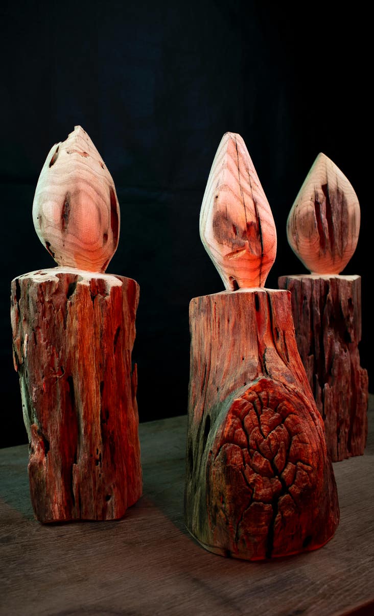 Scultura in legno riciclato raffigurante un set di candele accese.